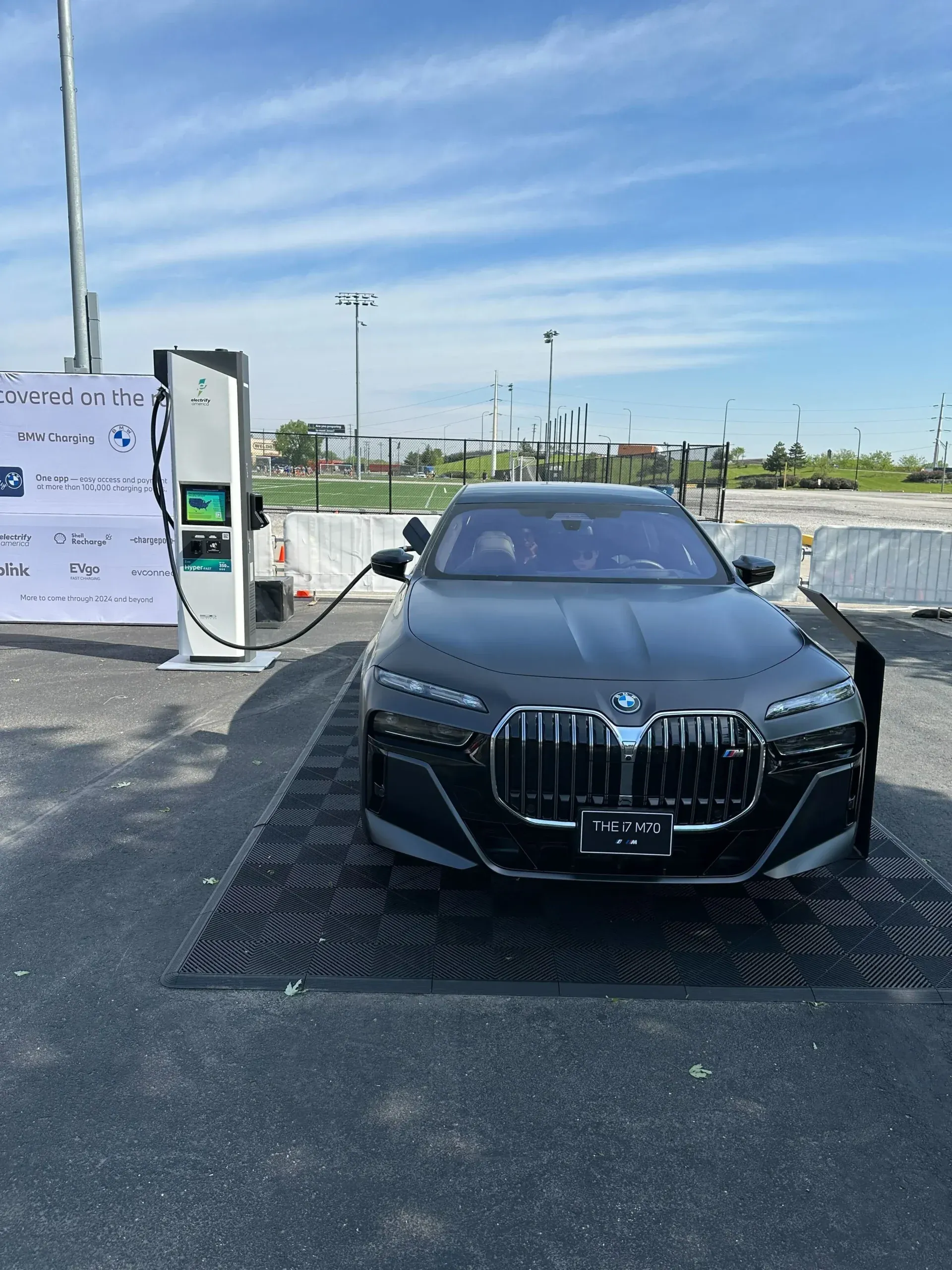 A BMW electric sedan on display beside a charging station at the event