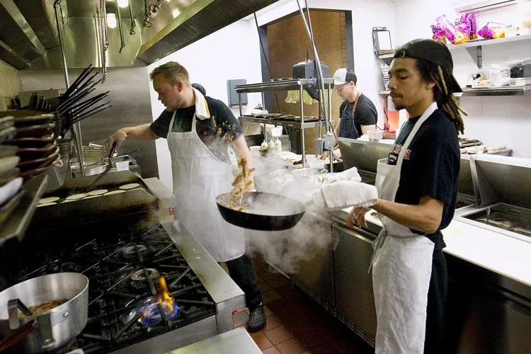 Chef John cooking over a flaming pan in the Mama Lu’s kitchen