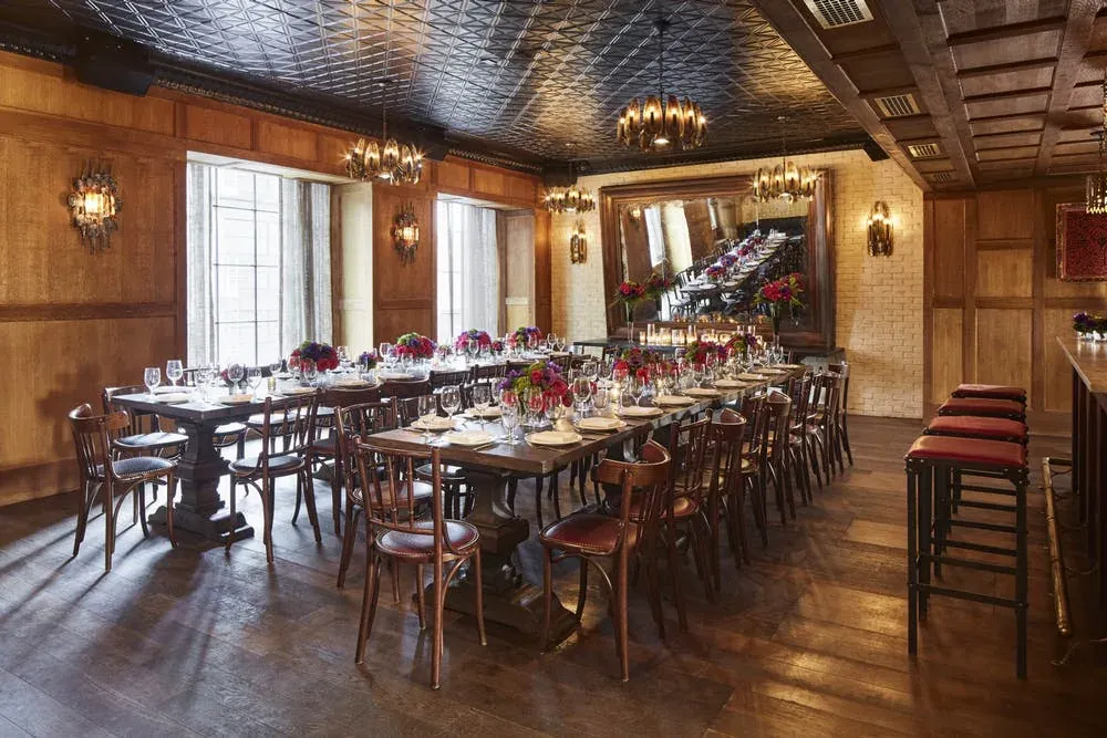 Dirty French private dining room with long tables set with flowers and glassware under chandeliers