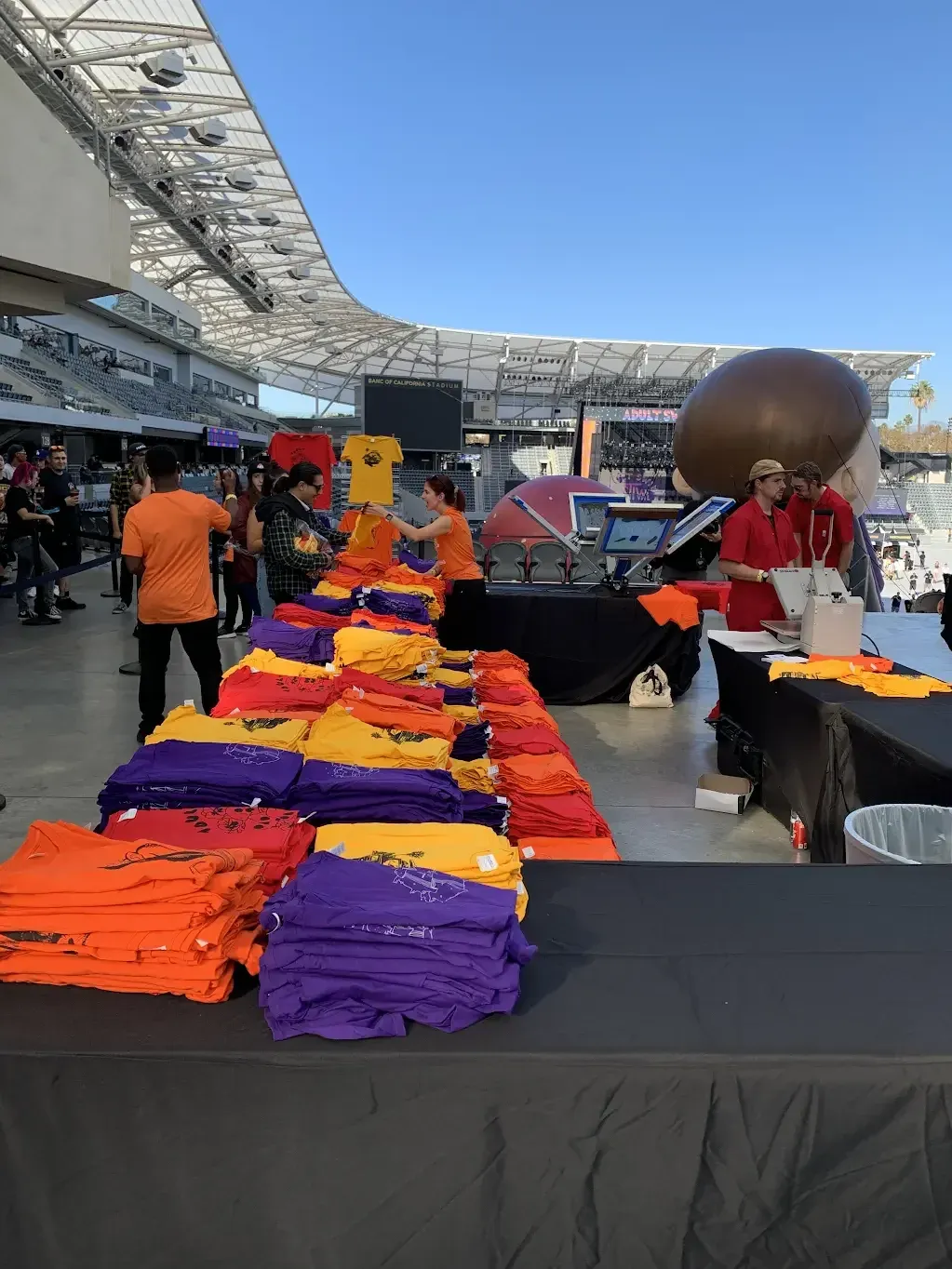 Folded festival shirts stacked at the embroidery station