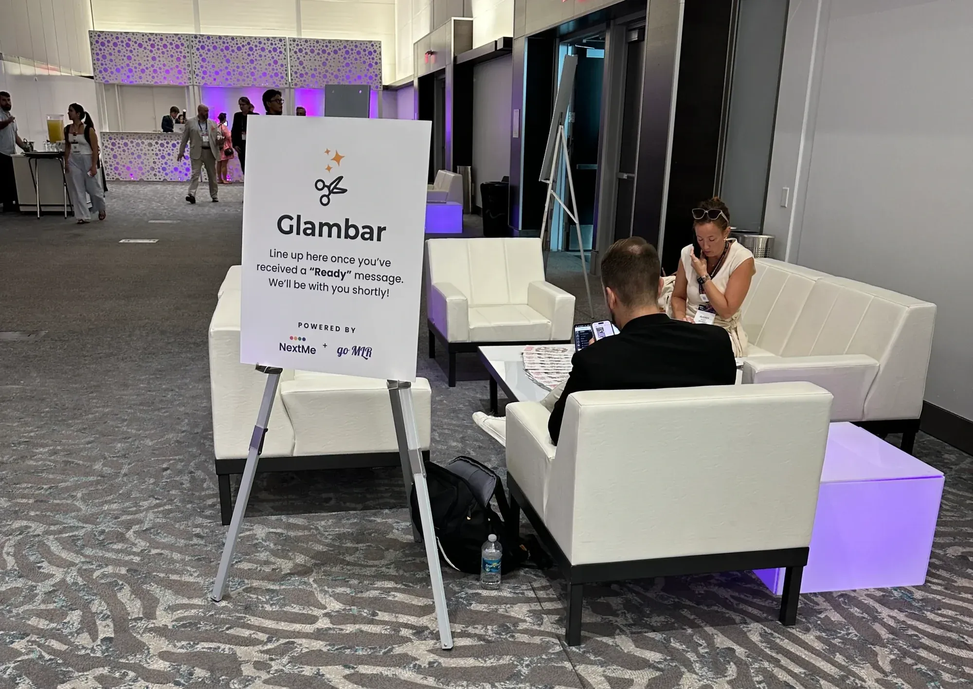 A NextMe and goMLR Glam Bar sign beside the lounge seating at the summit