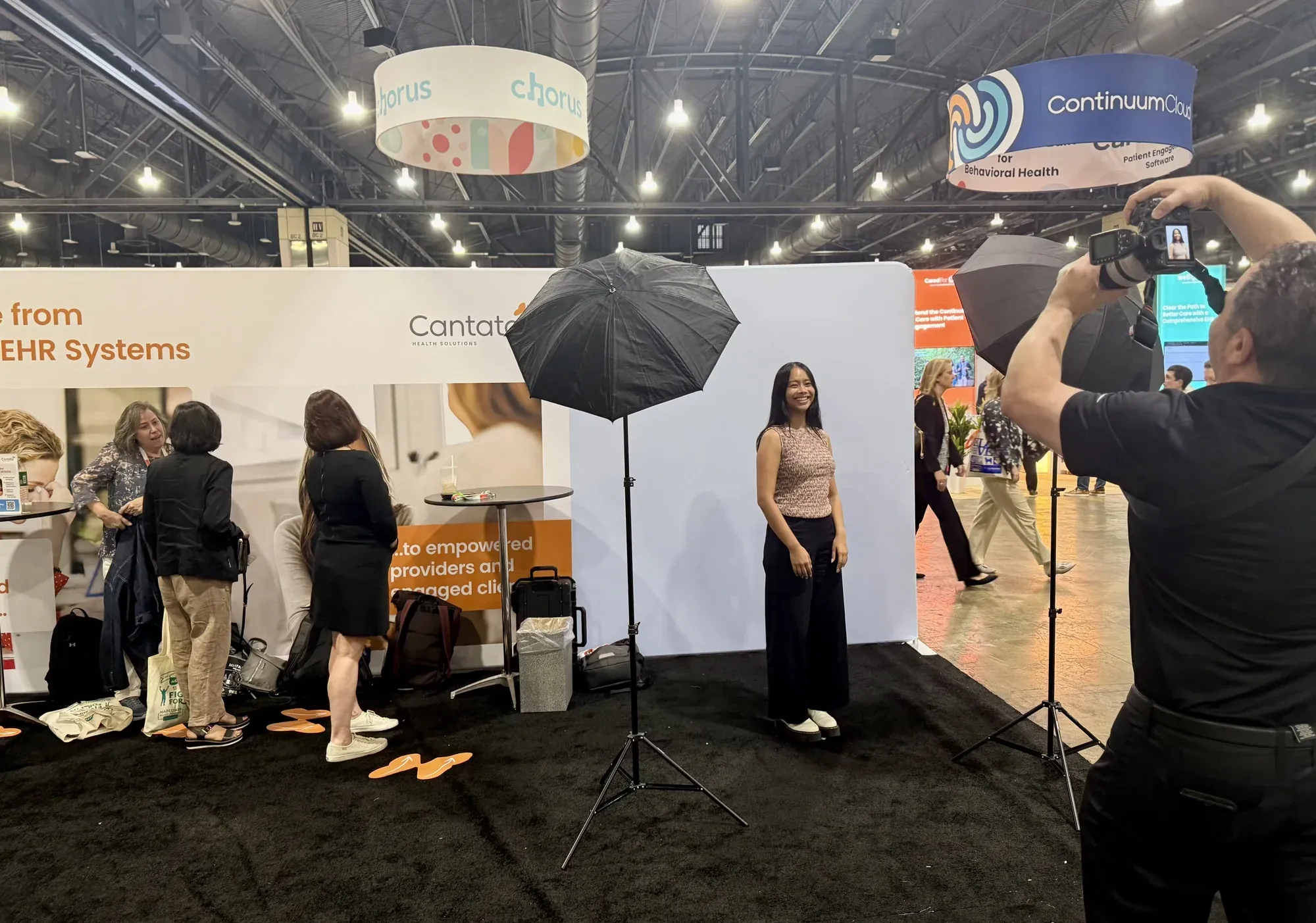 A photographer takes an attendee’s headshot at the Cantata Headshot Café booth at NatCon25