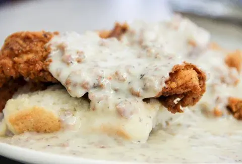 Close-up of chicken fried steak smothered in sausage gravy over a biscuit at HomeGrown
