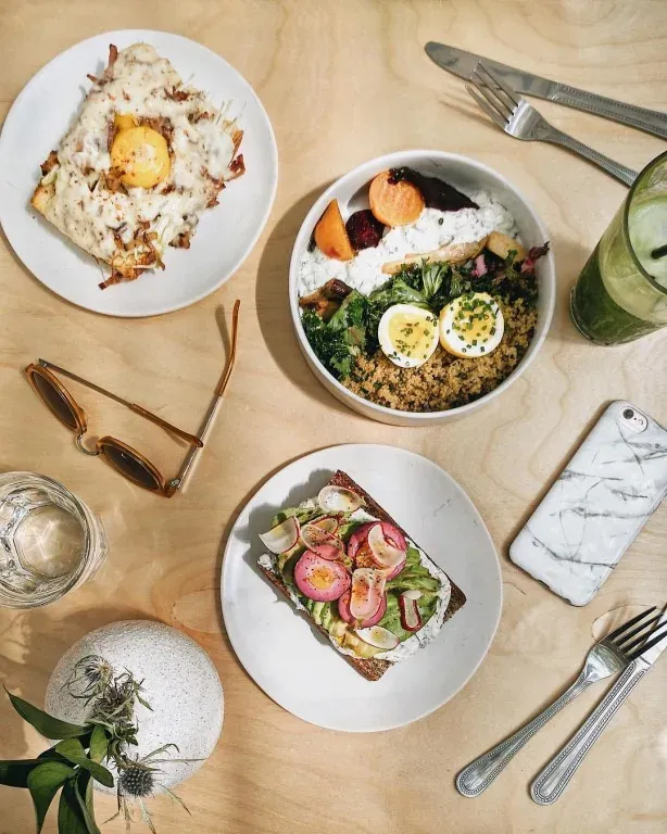 Overhead view of Loosie’s brunch with a grain bowl with eggs, avocado toast, and a cheesy egg-topped dish
