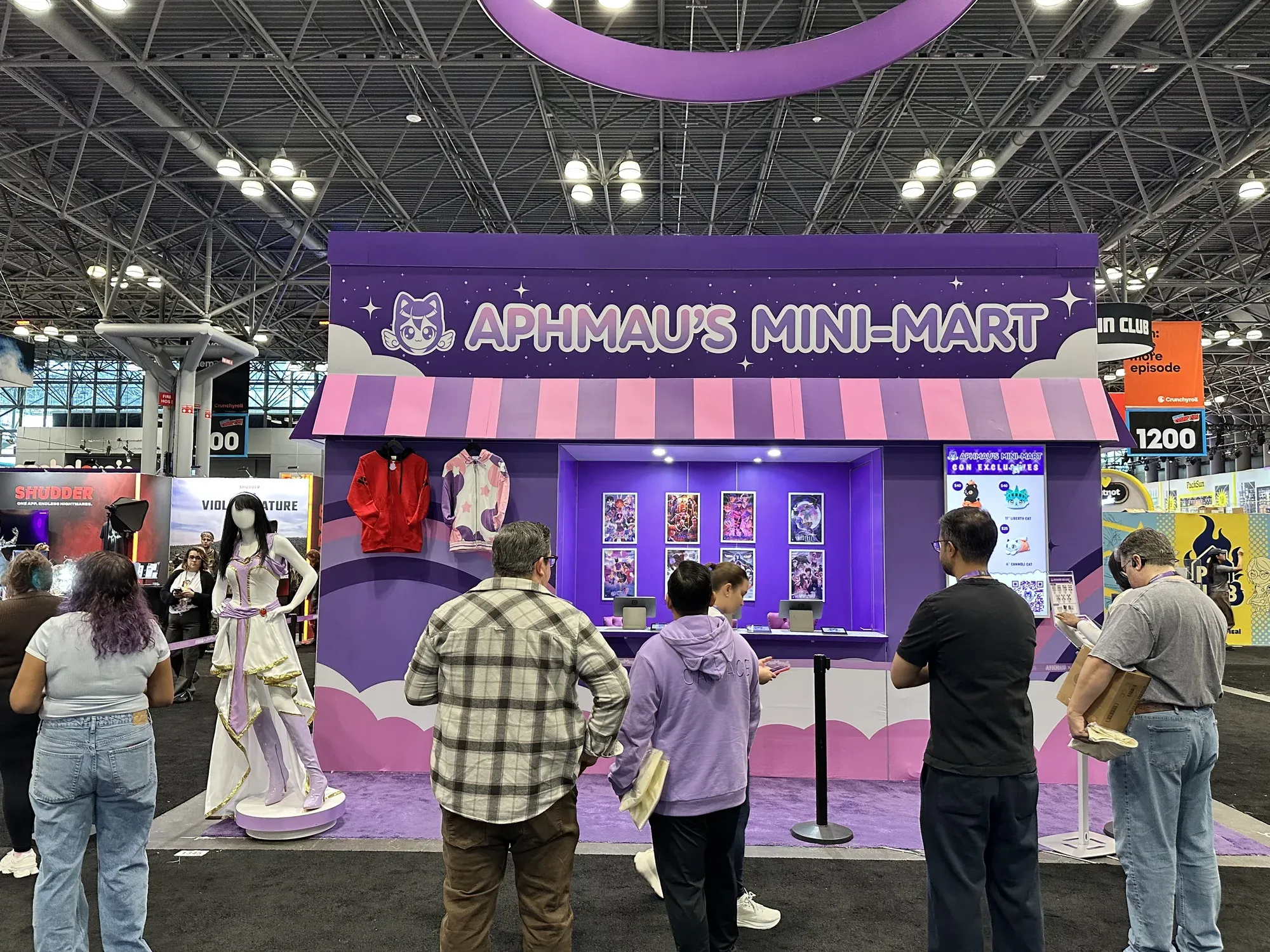 The front of Aphmau's Mini Mart at New York Comic Con, a purple storefront with a striped awning, with fans standing in front of it