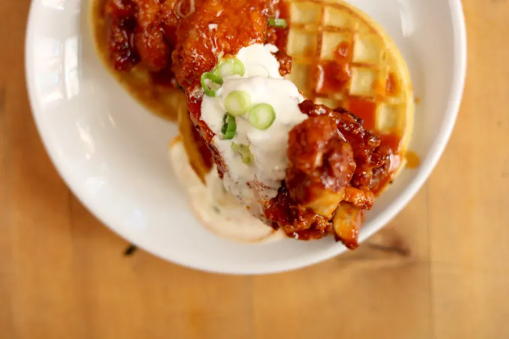 Mother’s Ruin fried chicken and waffle in hot sauce topped with ranch and scallions