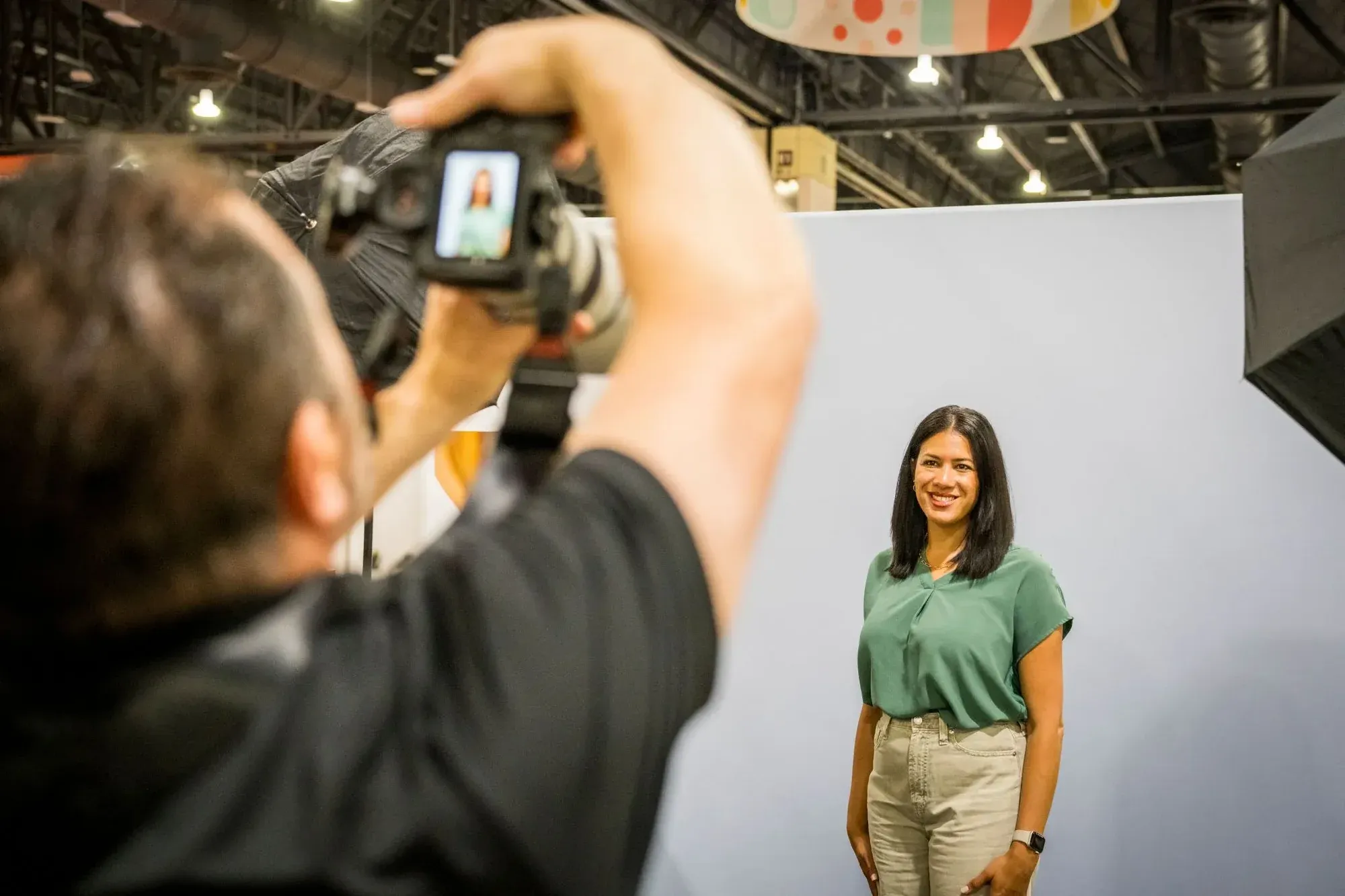 A photographer takes a headshot of an attendee in front of a white backdrop