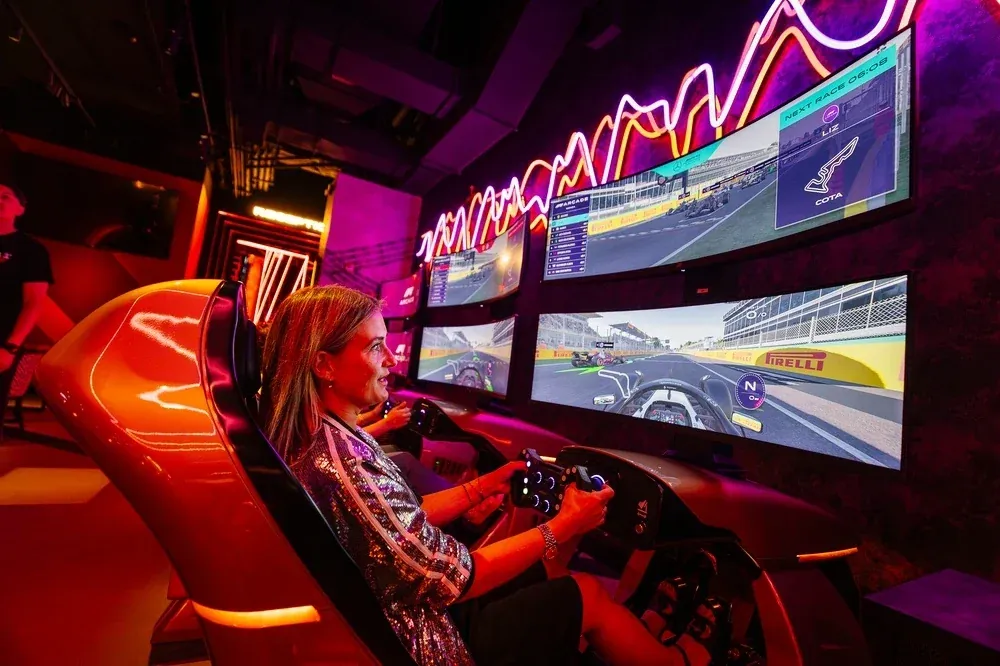 A guest racing on an F1 Arcade simulator in front of a wall of screens