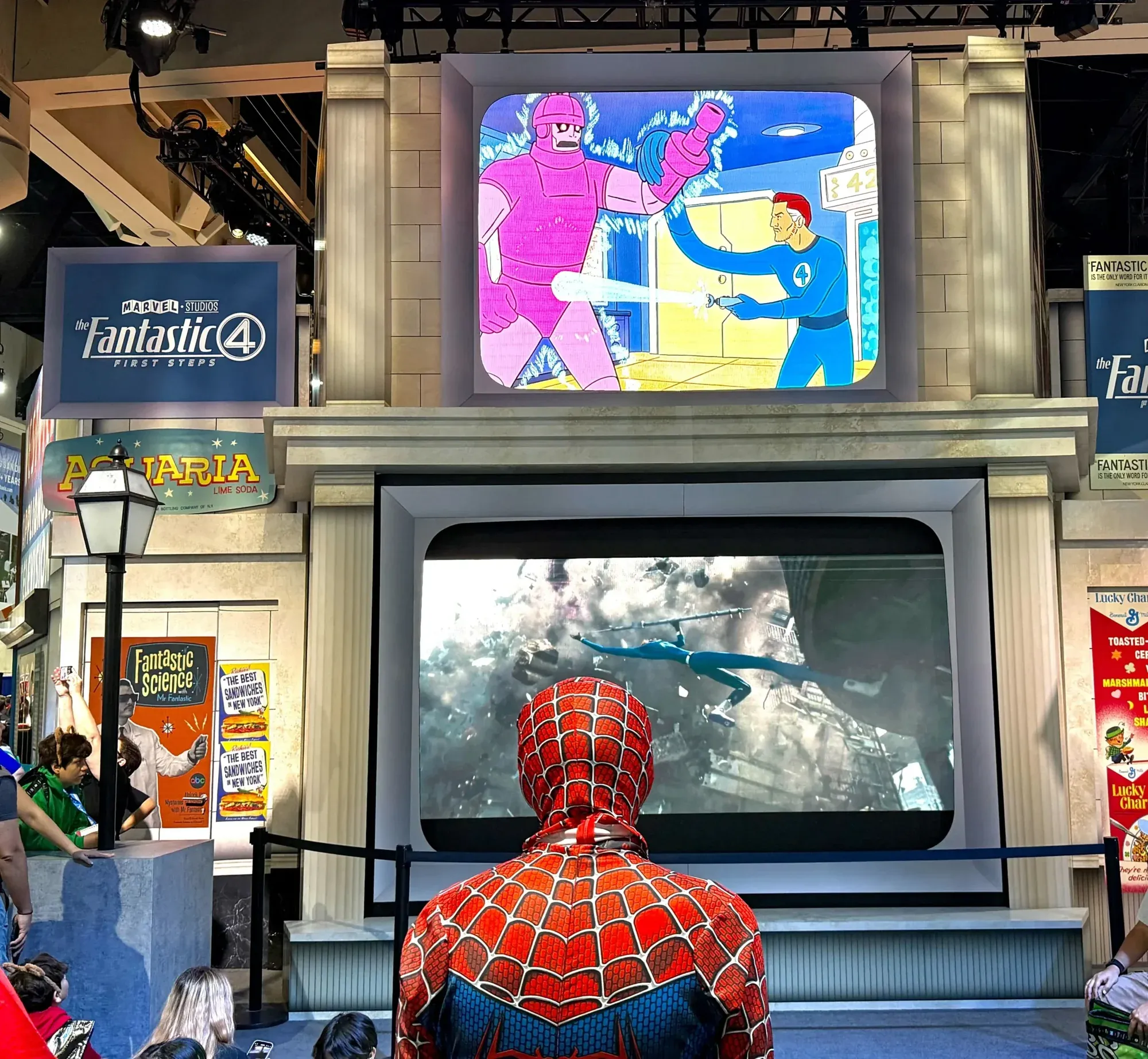 A fan dressed as Spider-Man watching a screen on the Fantastic Four set at the Marvel booth