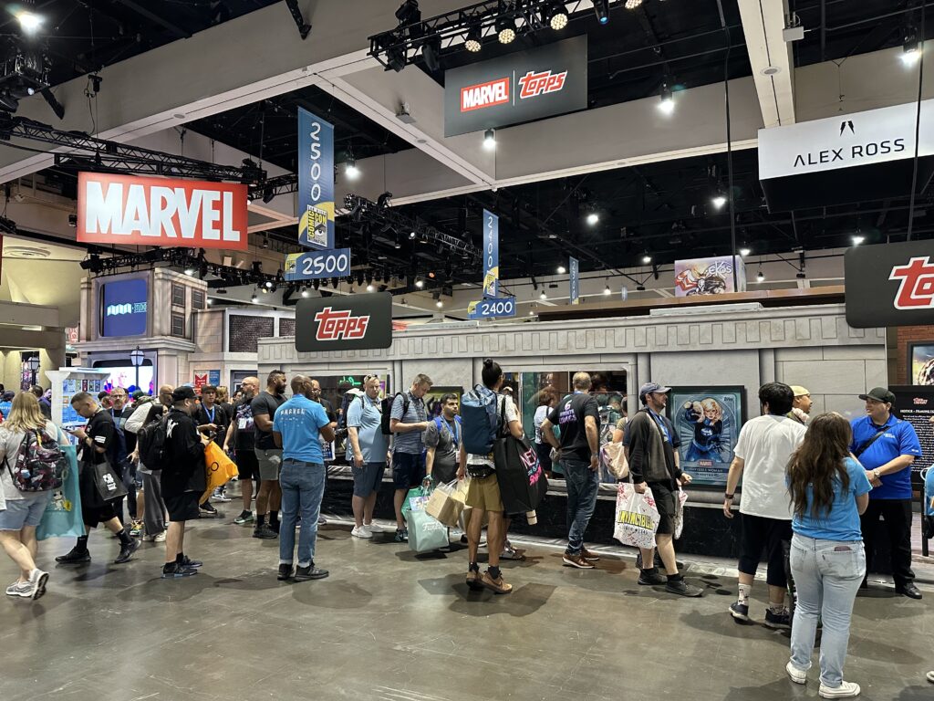 Attendees waiting in a long physical line at the Topps and Marvel booth during San Diego Comic-Con.